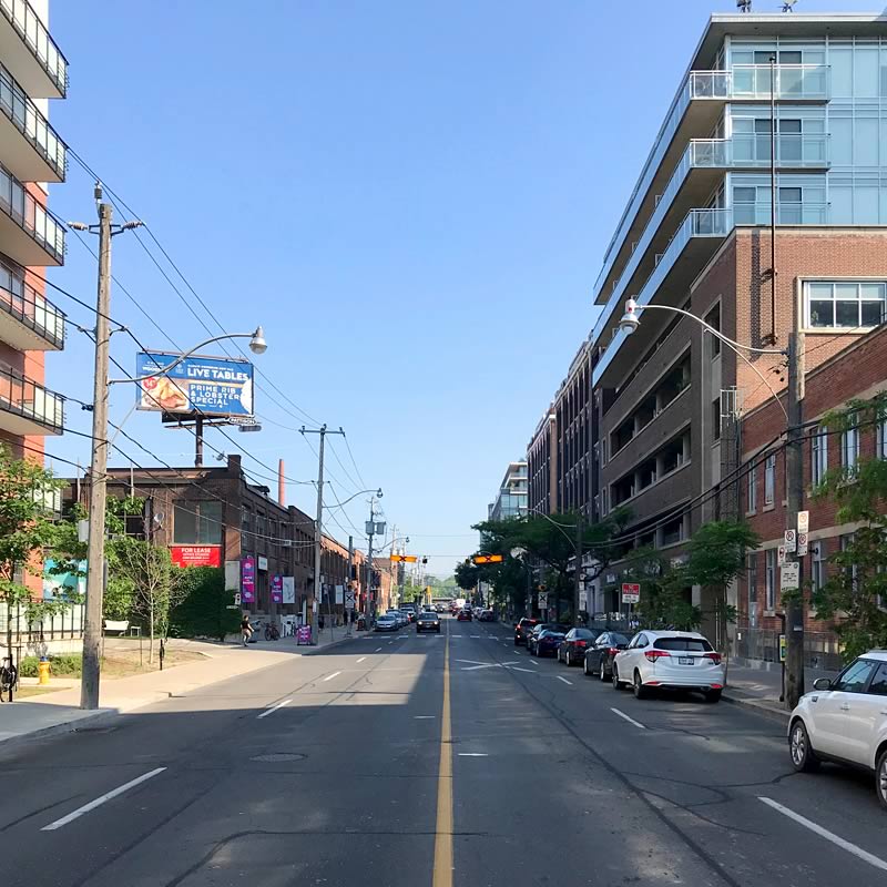 View north on Carlaw Avenue from the intersection of Natalie Street showing several former factory buildings that have been adapted into condominiums or live-work spaces.