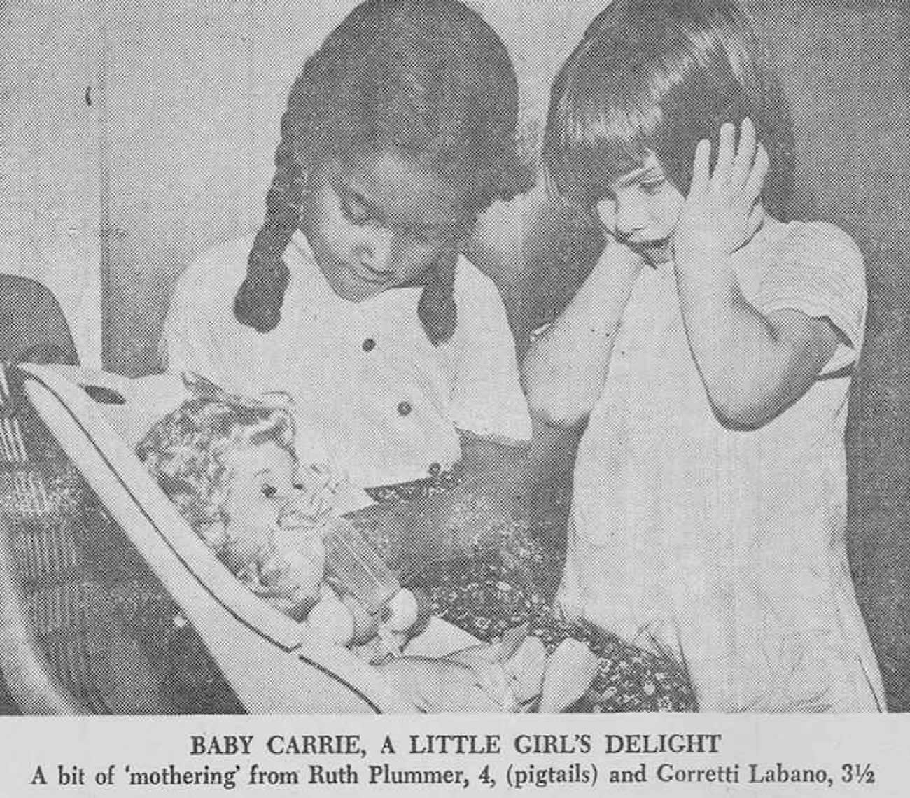 Two little girls looking at a doll with excitement.