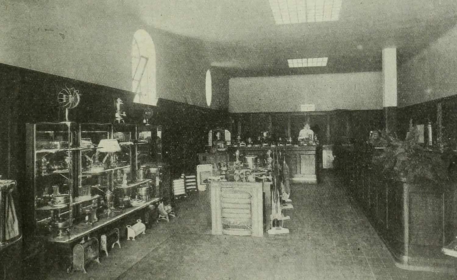 Black and white image of the interior of a store with early electrical domestic devices on display.